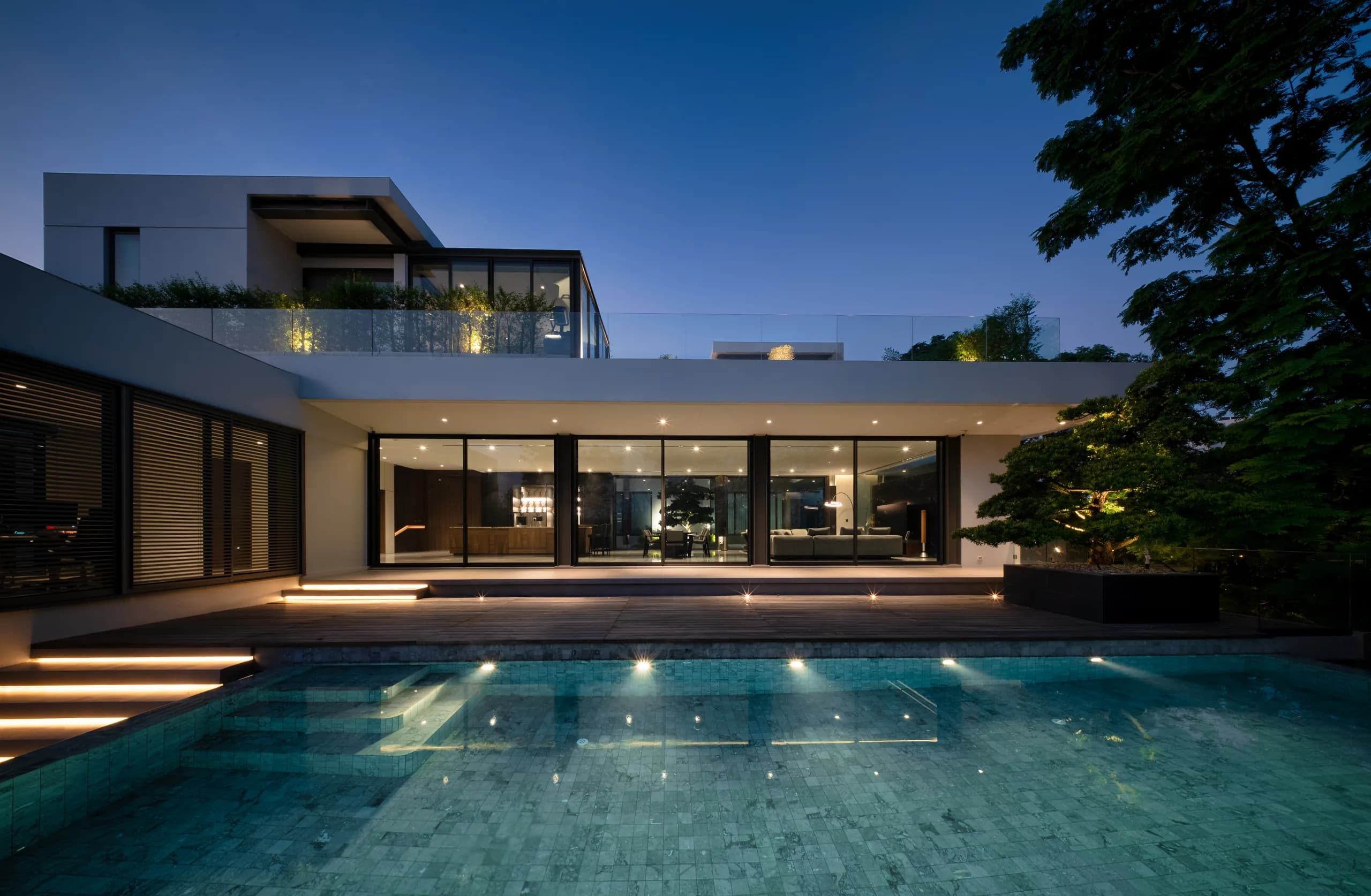 Luxury MARDISA villa exterior at twilight with illuminated infinity pool